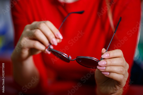 Beautiful young girl chooses sunglasses in an optics store.