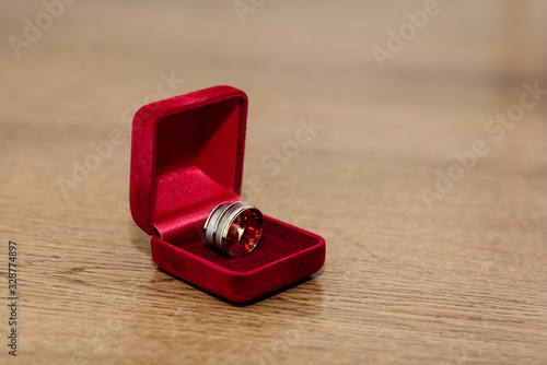 Wedding rings in a box of red velvet on a wooden table. Close up © Hyusein