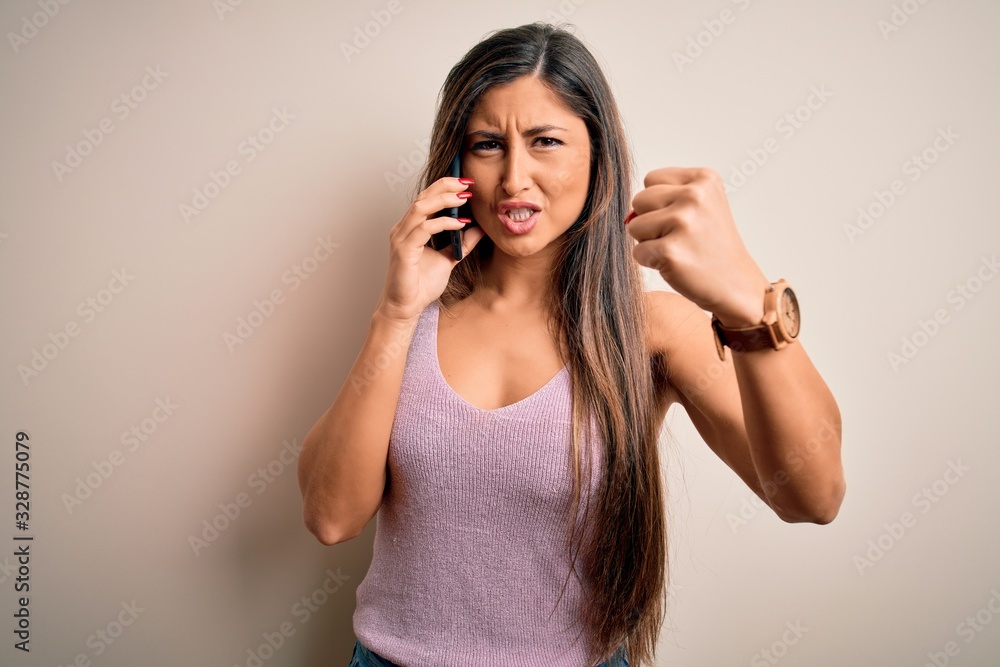 Young brunette woman having conversation talking on the smartphone over white background annoyed and frustrated shouting with anger, crazy and yelling with raised hand, anger concept Young brunette woman having conversation talking on the smartphone over white background annoyed and frustrated shouting with anger, crazy and yelling with raised hand, anger concept