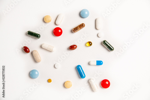 Multicolored medical pills and capsules on a white background, top view