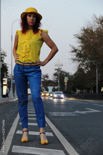 a woman stands on the road markings, in the evening in urban conditions, car lights in the distance, blur