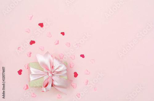 Present with red bow on pink background with tittle sparkles. Flat lay trendy style.