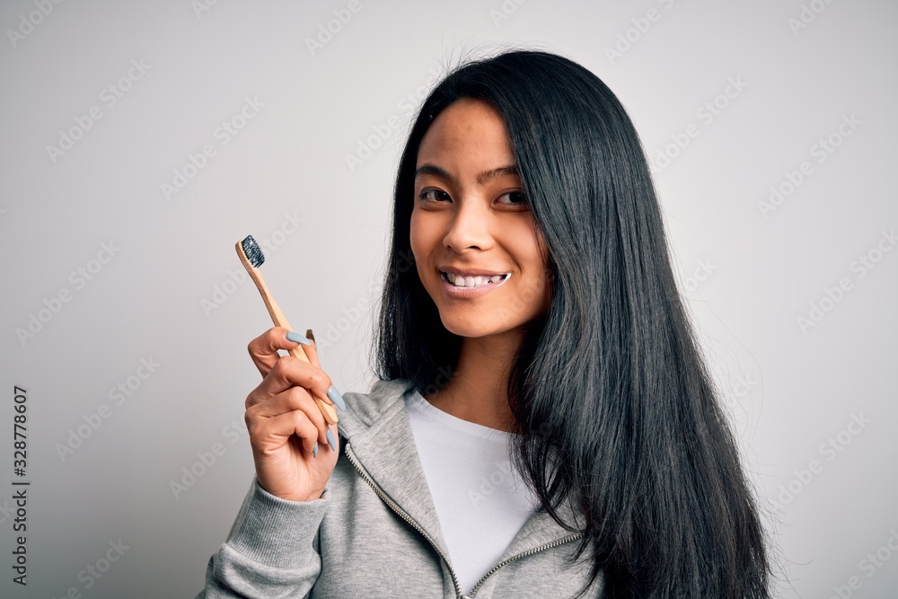Young beautiful woman smiling happy. Standing with smile on face whasing tooth using toothbrush over isolated white background Young beautiful woman smiling happy. Standing with smile on face whasing tooth using toothbrush over isolated white background