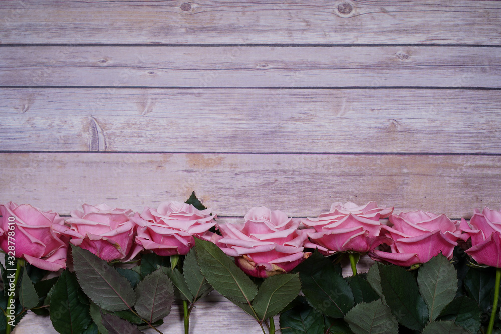 Pink roses on wooden background. Empty space for design.
