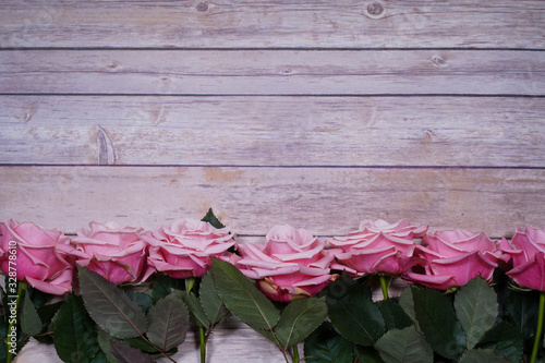 Pink roses on wooden background. Empty space for design. photo