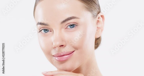 Close up of beautiful young woman with blue eyes and perfect skin touching face with hands, isolated on white  background. Skin care and natural beauty concept