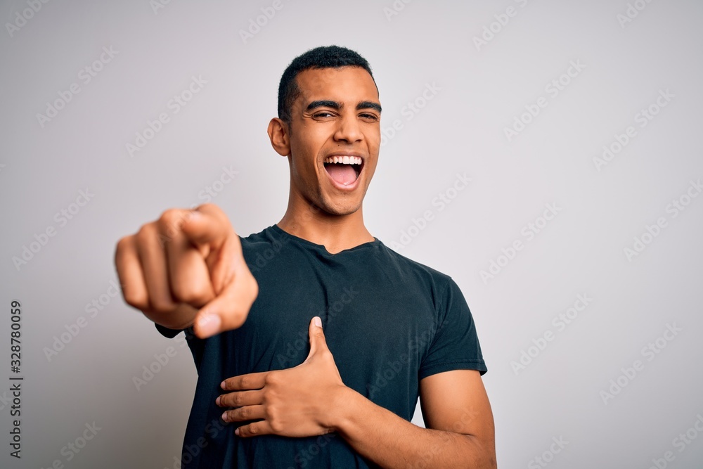 Young handsome african american man wearing casual t-shirt standing over white background laughing at you, pointing finger to the camera with hand over body, shame expression Young handsome african american man wearing casual t-shirt standing over white background laughing at you, pointing finger to the camera with hand over body, shame expression