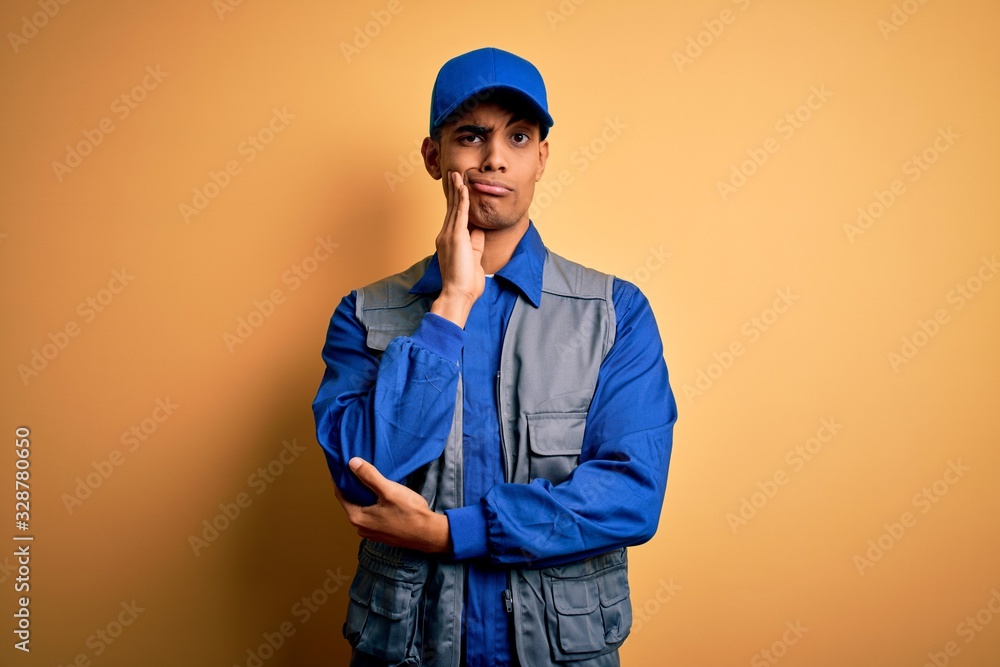 Young handsome african american handyman wearing worker uniform and cap thinking looking tired and bored with depression problems with crossed arms.
