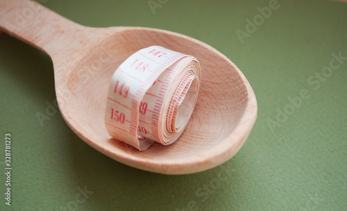 Tape measure on a wooden spoon. Healthy lifestyle. Lose Weight By Summer. Proper nutrition. Diet.