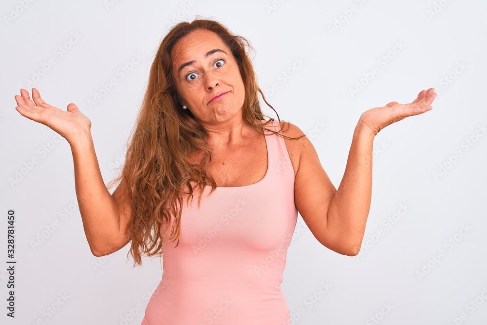 Middle age mature woman standing over white isolated background clueless and confused expression with arms and hands raised. Doubt concept. Middle age mature woman standing over white isolated background clueless and confused expression with arms and hands raised. Doubt concept.