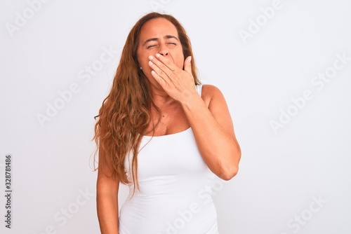 Middle age mature woman standing over white isolated background bored yawning tired covering mouth with hand. Restless and sleepiness.