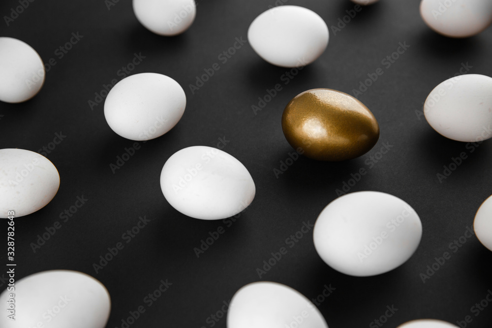 White and gols eggs arranged on black background