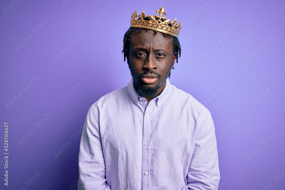 Young african american man wearing golden crown of king over isolated purple background skeptic and nervous, frowning upset because of problem. Negative person. Young african american man wearing golden crown of king over isolated purple background skeptic and nervous, frowning upset because of problem. Negative person.