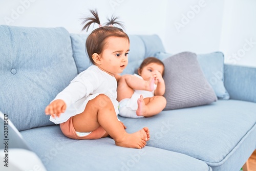 Beautiful infant happy girls playing together at home kindergarten sitting on the sofa