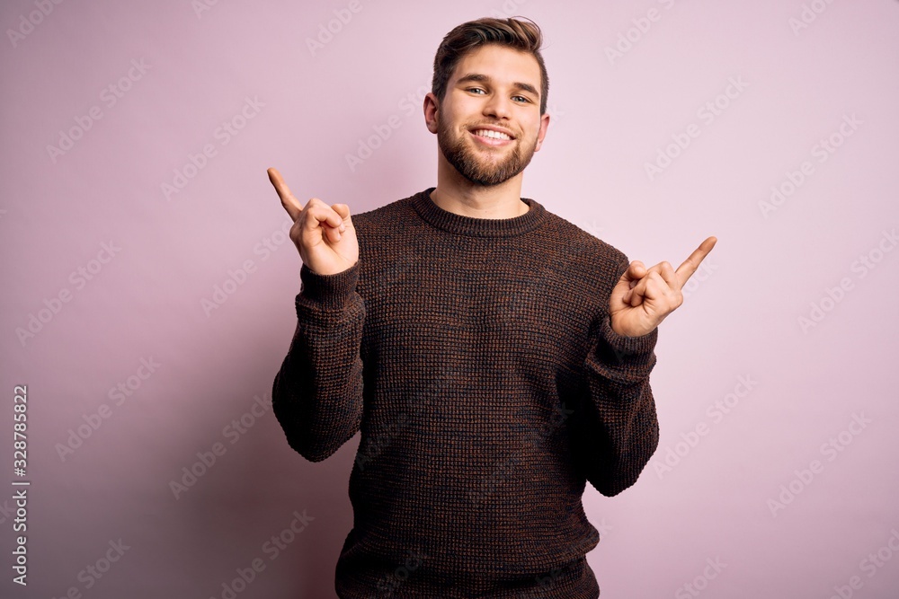 Young blond man with beard and blue eyes wearing casual sweater over pink background smiling confident pointing with fingers to different directions. Copy space for advertisement Young blond man with beard and blue eyes wearing casual sweater over pink background smiling confident pointing with fingers to different directions. Copy space for advertisement