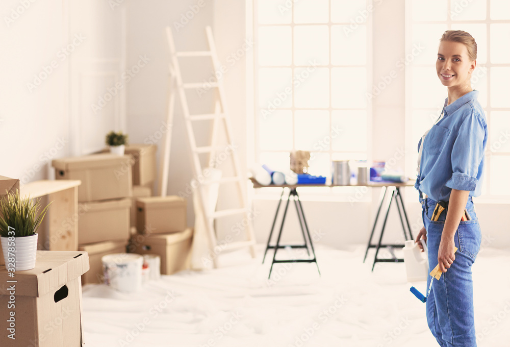 Pretty smilling woman painting interior wall of home with paint roller Pretty smilling woman painting interior wall of home with paint roller