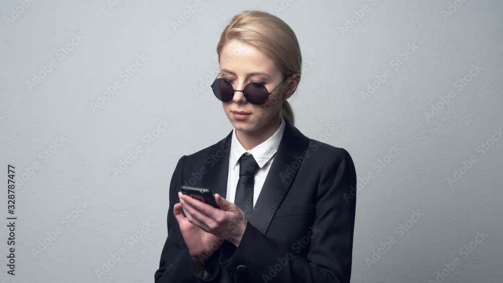businesswoman in a classic business suit and tie using mobile phone businesswoman in a classic business suit and tie using mobile phone