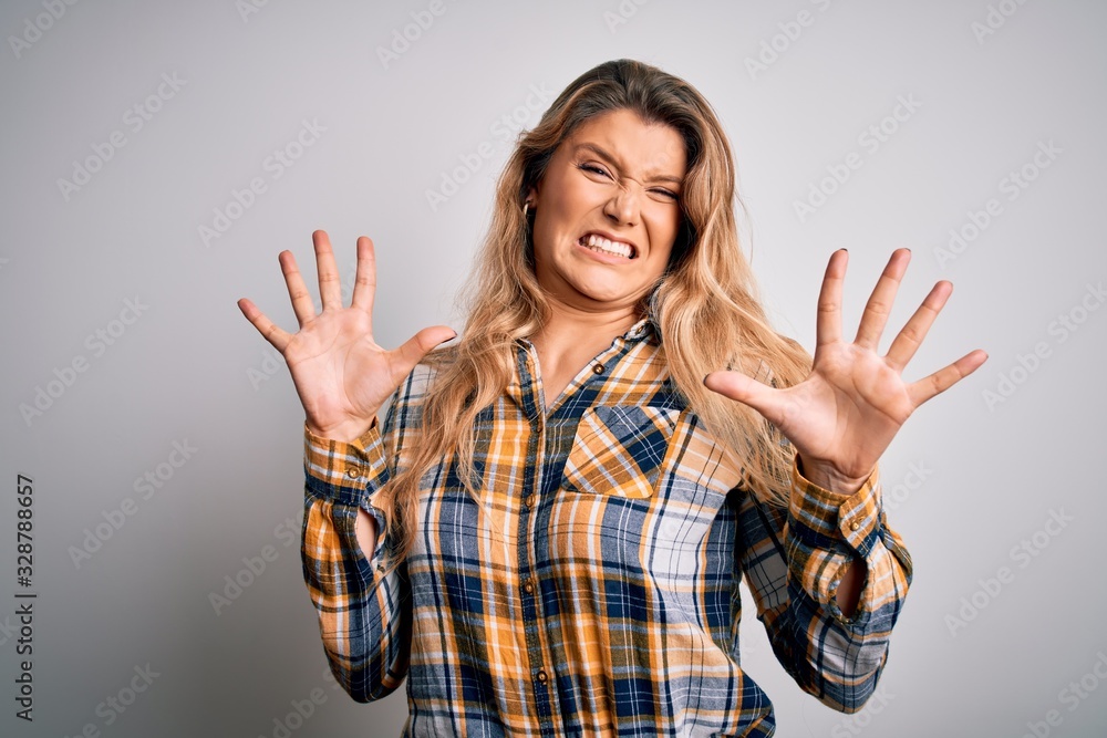 Young beautiful blonde woman wearing casual shirt standing over isolated white background afraid and terrified with fear expression stop gesture with hands, shouting in shock. Panic concept. Young beautiful blonde woman wearing casual shirt standing over isolated white background afraid and terrified with fear expression stop gesture with hands, shouting in shock. Panic concept.
