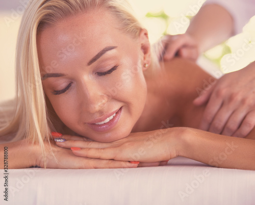 Young and beautiful girl relaxing in spa salon. Massage therapy over seasonal summer or spring background