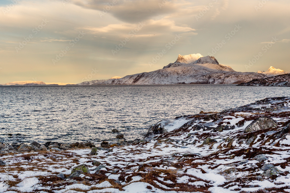 Obraz premium Frozen tundra landscape with cold greenlandic sea and snow Sermitsiaq mountain in the background, nearby Nuuk city, Greenland