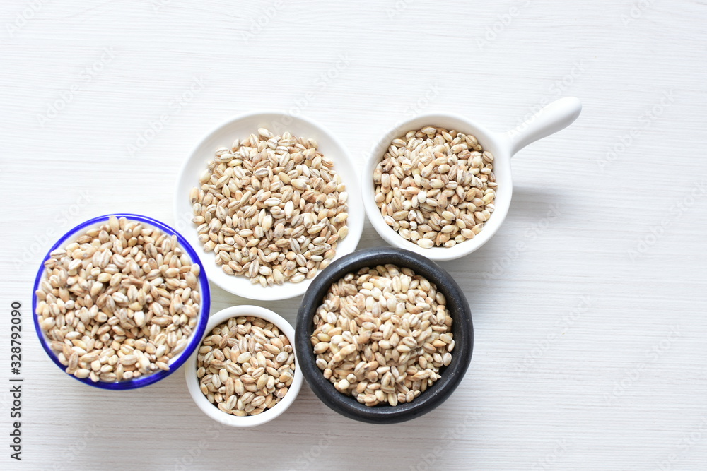 Raw barley grains, displayed in containers on textured background Raw barley grains, displayed in containers on textured background