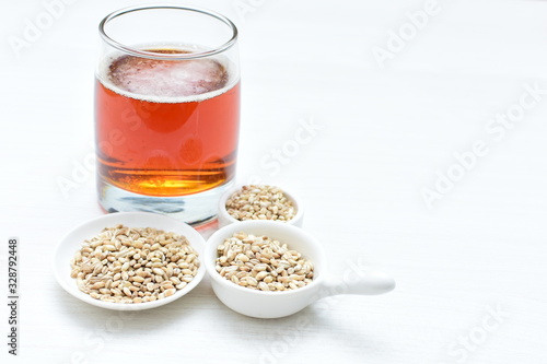 Raw barley grains, released in containers and accompanied by a glass of beer