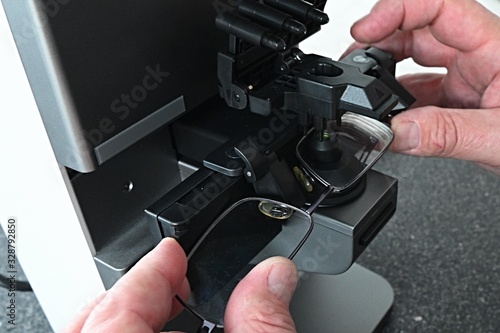 Hands of optometrist adjusting eyeglasses during measurement of dioptry with modern digital lens meter. 