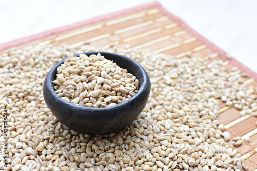 Raw barley grains, displayed in containers on textured background Raw barley grains, displayed in containers on textured background