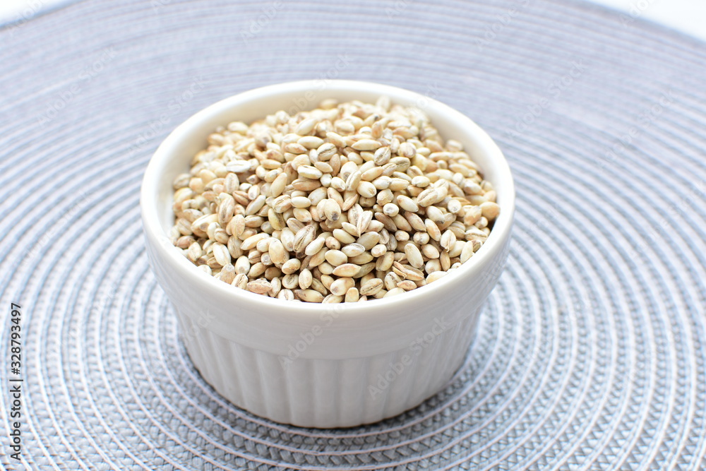 Raw barley grains, displayed in containers on textured background Raw barley grains, displayed in containers on textured background