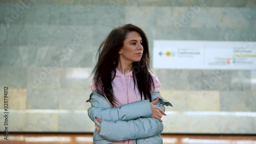 A young girl stands in front of a passing subway train and looks at the camera.