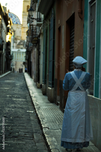 Woman wearing the outfit that nurses wore in ancient times. Nurse in a Spanish street at sunset time. © Concepcion RamalloM-