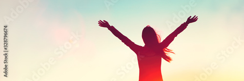 Happy woman sihouette with arms raised up in success on sunset glow sunshine ...