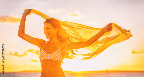 Healthy summer woman happy with arms up in freedom yellow scarf flying in the wind panoramic bannerr. Asian bikini girl for body care wax laser concept.
