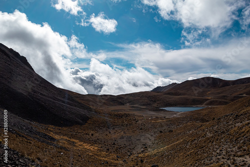 Paisaje volcánico de montañas, nubes y laguna