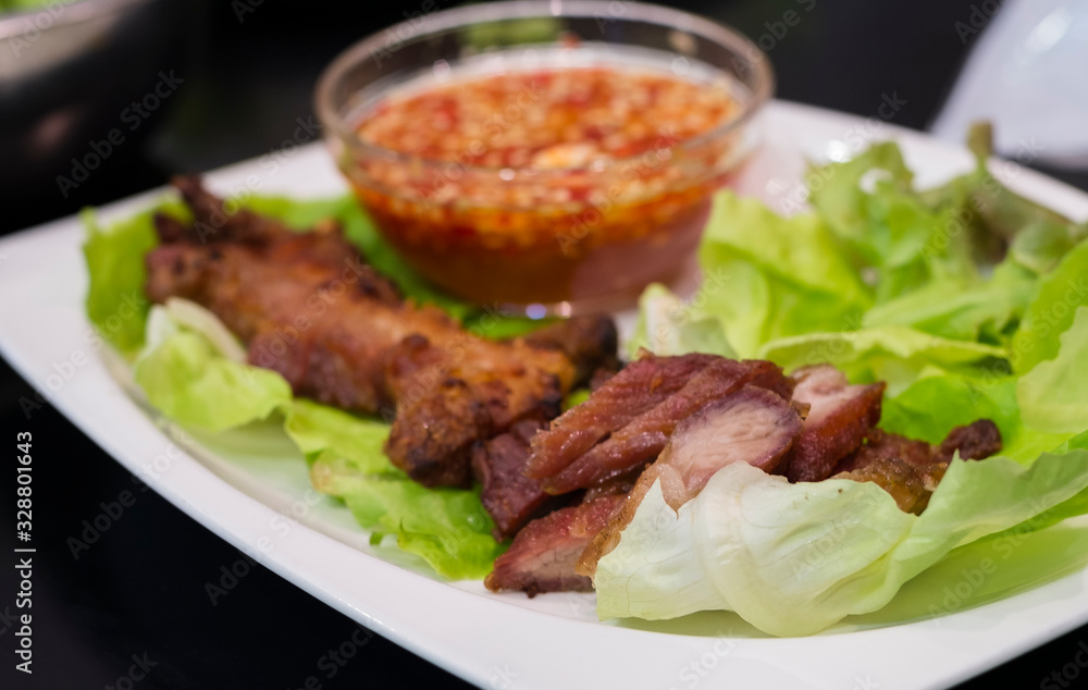 Thai roasted crispy pork on lettuce with Thai Spicy Sauce, Close up view Thai roasted crispy pork on lettuce with Thai Spicy Sauce, Close up view