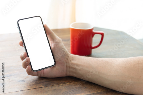Mockup image blank white screen cell phone.man hand holding texting using mobile on desk at coffee shop.background empty space for advertise text.people contact marketing business,technology