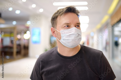 Man wearing disposable medical mask in airport or supermarket during coronavirus pneumonia outbreak photo