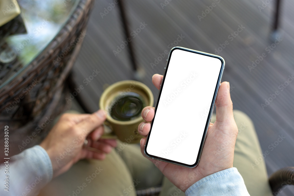 Mockup image blank white screen cell phone.man hand holding texting using mobile on desk at coffee shop.background empty space for advertise text.people contact marketing business,technology