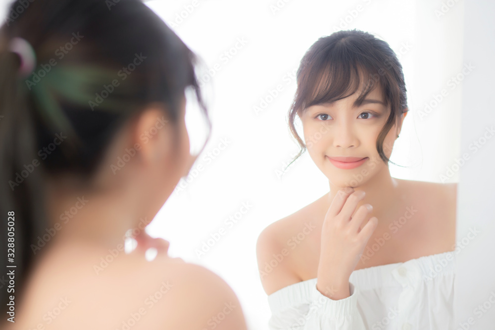 Beauty portrait young asian woman smiling look at mirror of checking skin care caucasian with wellness in the bedroom, beautiful girl happy touching face in reflection for health, lifestyle concept. Beauty portrait young asian woman smiling look at mirror of checking skin care caucasian with wellness in the bedroom, beautiful girl happy touching face in reflection for health, lifestyle concept.