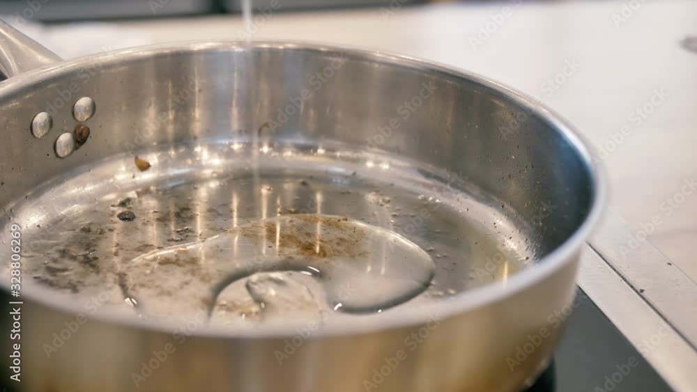 Olive oil is poured into the pan with a thin stream Olive oil is poured into the pan with a thin stream