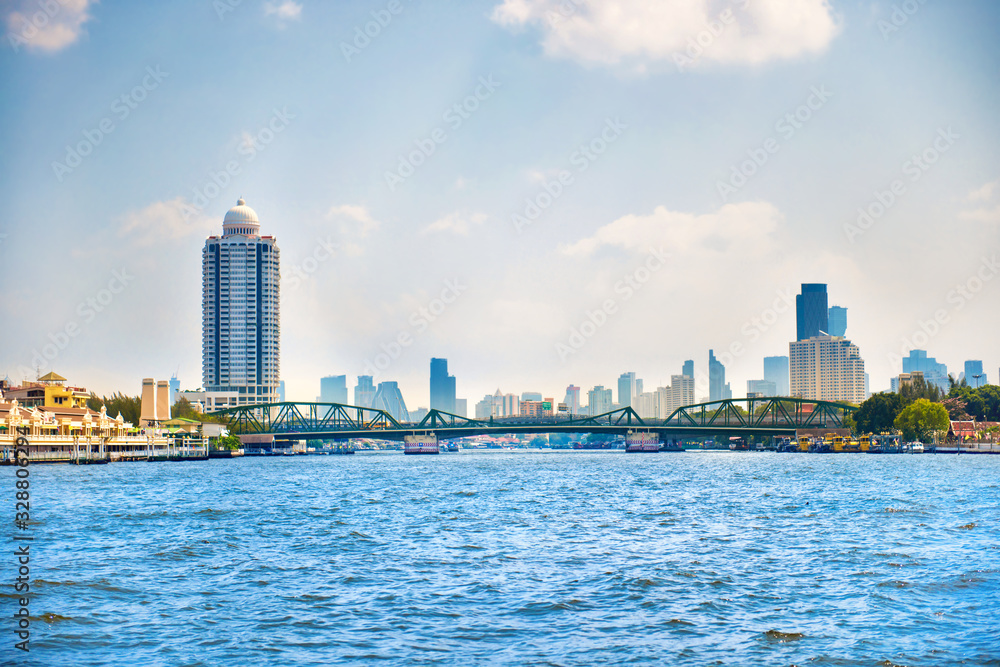 Obraz premium Cityscape view with Chao Phraya river, steel Memorial bridge and skyscrapers of downtown on background. Bangkok, Thailand