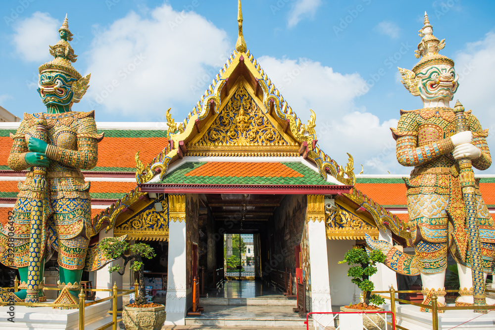 View of bright colored and gold decorated gates with two mythical demon guardians. Grand Palace, Bangkok, Thailand