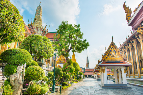 View of inner court of Temple of Emerald Buddha with ornate buildings and trees. Grand Palace complex, Bangkok, Thailand