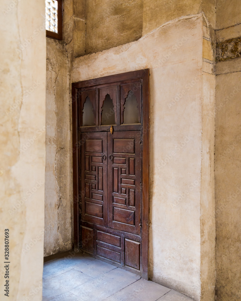 Angle view of wooden aged door on grunge stone wall, Medieval Cairo, Egypt