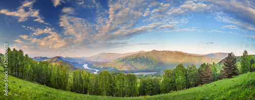Panoramic view of spring nature. Sunset sky, green meadows and forests.