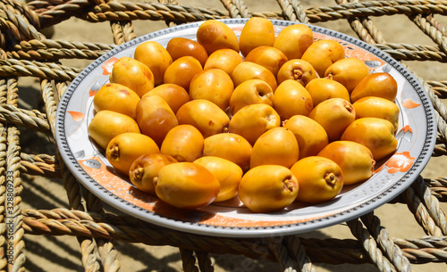 yellow unripe dates sweet fruit in plate close up, nature energy source diet healthy nutrition food photo
