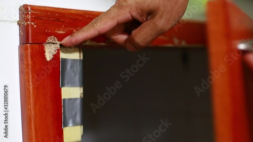 Termite elimination staff is pointing the termites to destroy wooden doors in the kitchen and the location of termite hunters. Selective focus to baits station on wooden door damaged. 