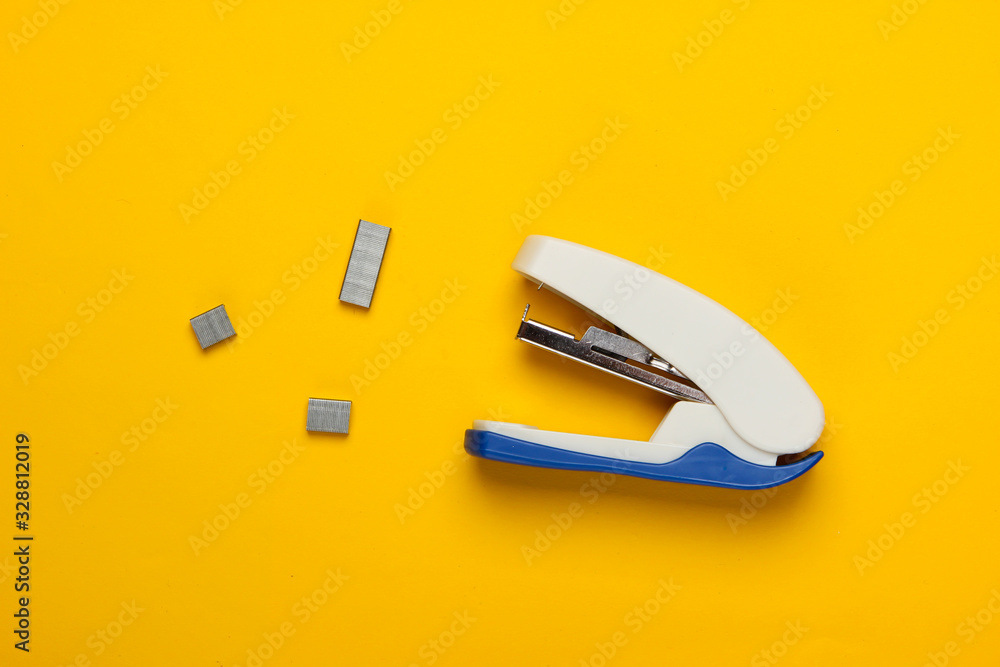 Stapler with paper clips on yellow background. Minimalism. Top view Stapler with paper clips on yellow background. Minimalism. Top view