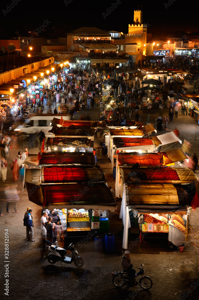Obraz premium Overview of crowds at food booths and shops at night in Place Djemaa el Fna square Marrakech Morocco