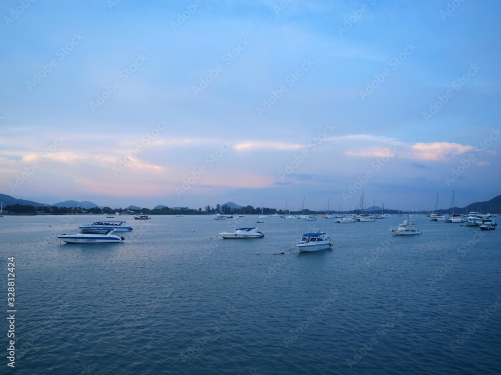 Pink gleams of sunset on the sky. Sea bay and anchored boats in the evening. Panorama of seascape.